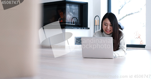 Image of Asian woman using laptop on floor