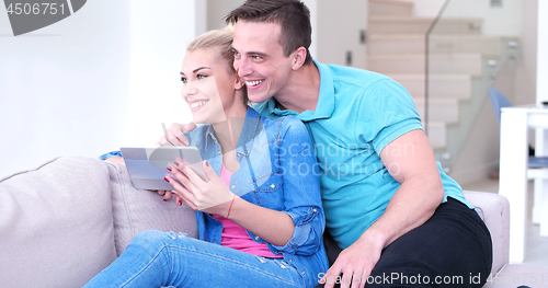 Image of couple relaxing at  home with tablet computers