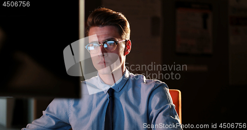 Image of man working on computer in dark office