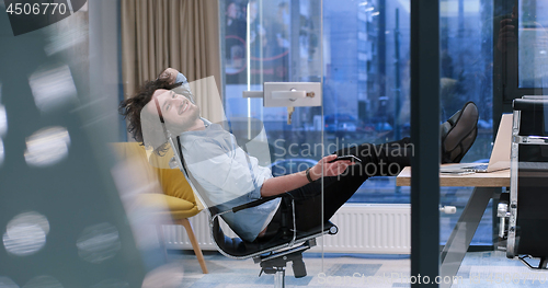 Image of businessman sitting with legs on desk