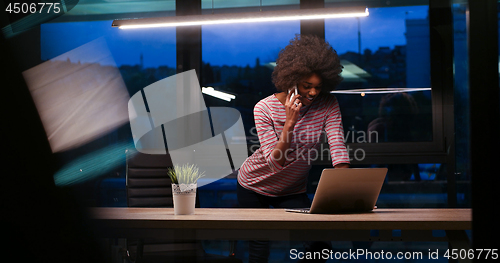 Image of black businesswoman using a laptop in night startup office