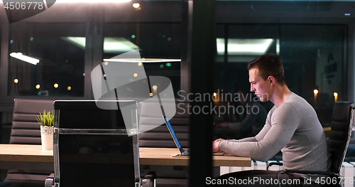 Image of man working on laptop in dark office