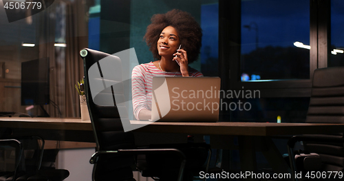 Image of black businesswoman using a laptop in night startup office