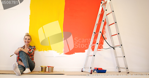 Image of young female painter sitting on floor