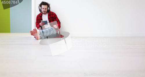 Image of young man listenig music on tablet at home