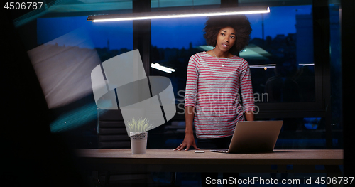 Image of black businesswoman using a laptop in night startup office