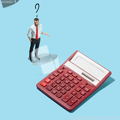 Image of Nerd young man with calculator isolated on blue