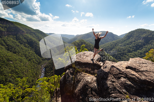 Image of Spirited woman jumping on a high cliff ledge.