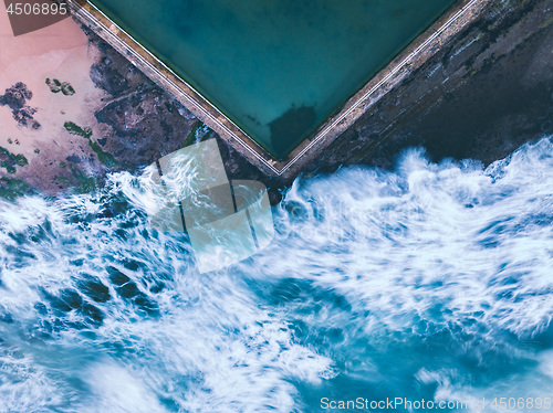 Image of Wavs encrouch upon the rock pool like fluid fingers