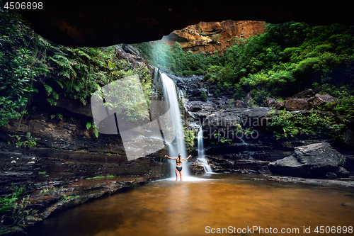Image of Woman cooling off in a mountain oasis and waterfall