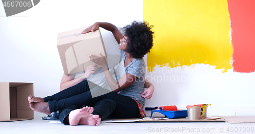 Image of young multiethnic couple playing with cardboard boxes