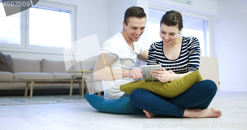 Image of Young Couple using digital tablet on the floor