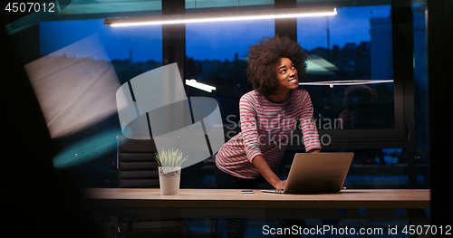 Image of black businesswoman using a laptop in night startup office