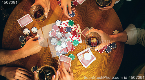 Image of Top view photo of friends sitting at wooden table. Friends having fun while playing board game.