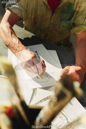 Image of Close up man working of Architect sketching a construction project on his plane project at site construction work