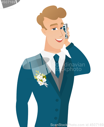 Image of Young caucasian groom talking on a mobile phone.