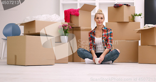 Image of woman with many cardboard boxes sitting on floor