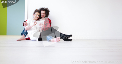 Image of Young Couple using digital tablet on the floor