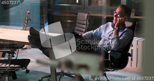 Image of businessman sitting with legs on desk at office