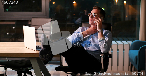Image of businessman sitting with legs on desk at office