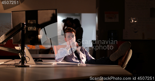 Image of businessman sitting with legs on desk at office