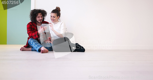 Image of Young Couple using digital tablet on the floor