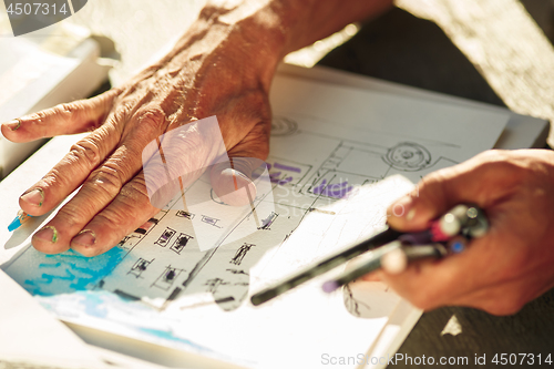 Image of Close up man working of Architect sketching a construction project on his plane project at site construction work