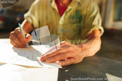 Image of Close up man working of Architect sketching a construction project on his plane project at site construction work
