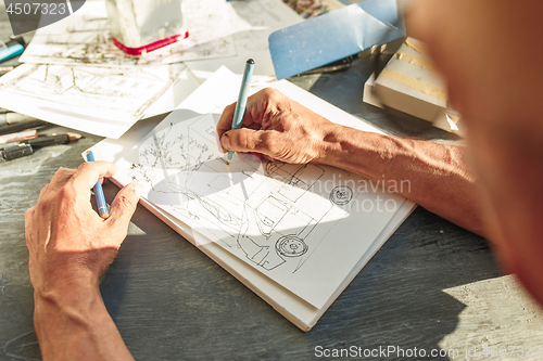 Image of Close up man working of Architect sketching a construction project on his plane project at site construction work