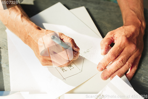 Image of Close up man working of Architect sketching a construction project on his plane project at site construction work