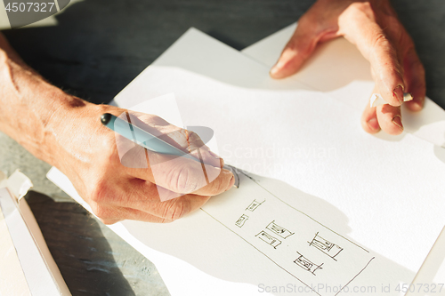 Image of Close up man working of Architect sketching a construction project on his plane project at site construction work