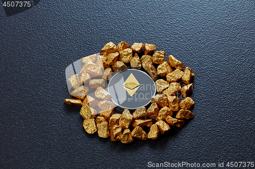 Image of Etereum coin and golden nuggets on a black concrete background. Business, finance and technology concept.