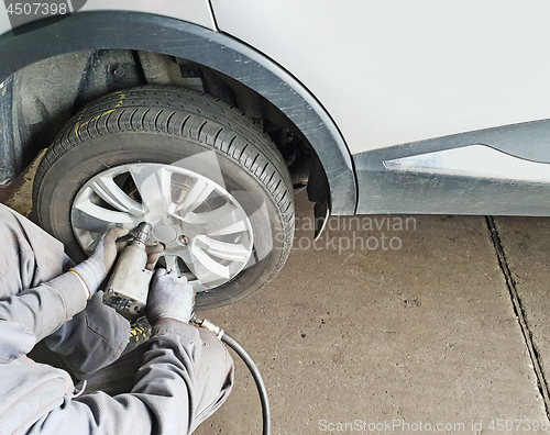 Image of Worker changes the car's tire