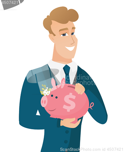 Image of Caucasian groom holding a piggy bank.