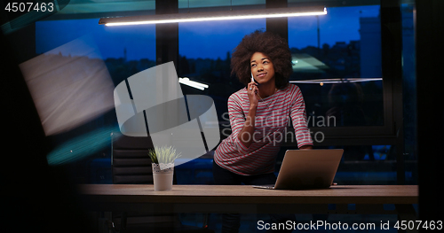 Image of black businesswoman using a laptop in night startup office