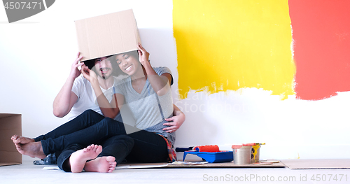 Image of young multiethnic couple playing with cardboard boxes