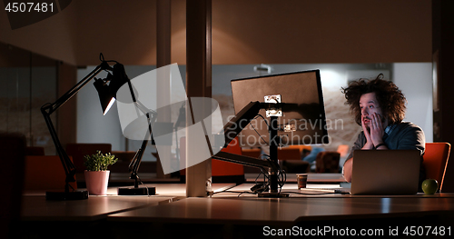 Image of man working on computer in dark office