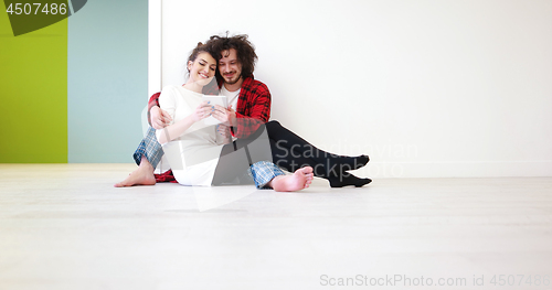 Image of Young Couple using digital tablet on the floor