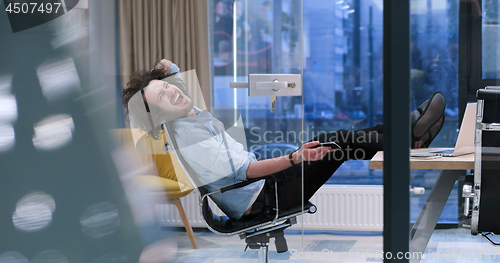 Image of businessman sitting with legs on desk