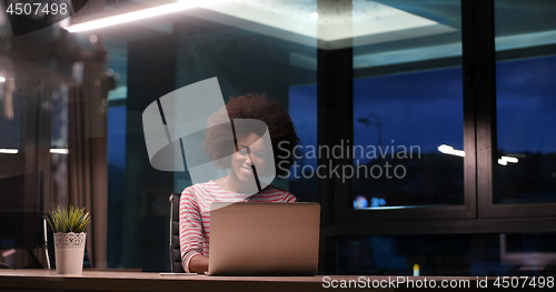 Image of black businesswoman using a laptop in night startup office