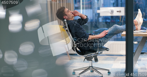 Image of businessman sitting with legs on desk