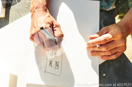 Image of Close up man working of Architect sketching a construction project on his plane project at site construction work