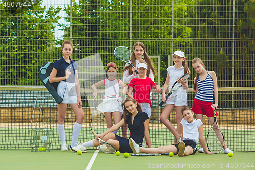 Image of Portrait of group of girls as tennis players holding tennis racket against green grass of outdoor court