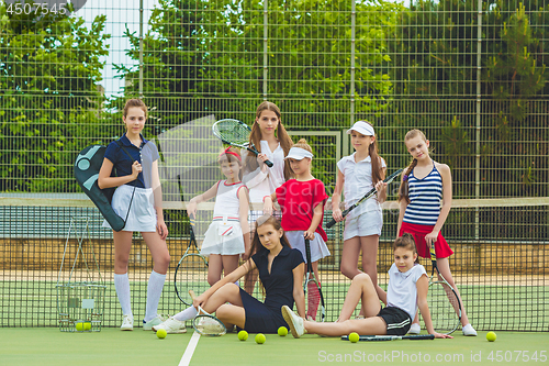 Image of Portrait of group of girls as tennis players holding tennis racket against green grass of outdoor court