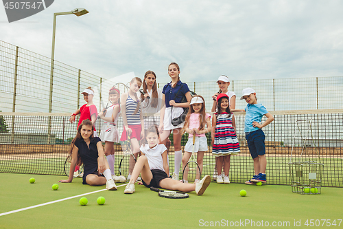 Image of Portrait of group of girls as tennis players holding tennis racket against green grass of outdoor court