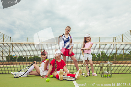 Image of Portrait of group of girls as tennis players holding tennis racket against green grass of outdoor court