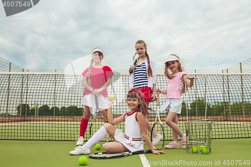 Image of Portrait of group of girls as tennis players holding tennis racket against green grass of outdoor court