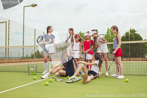 Image of Portrait of group of girls as tennis players holding tennis racket against green grass of outdoor court