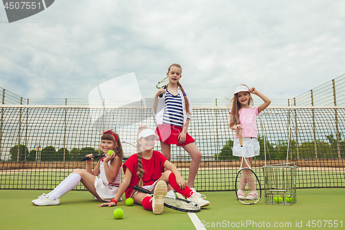 Image of Portrait of group of girls as tennis players holding tennis racket against green grass of outdoor court