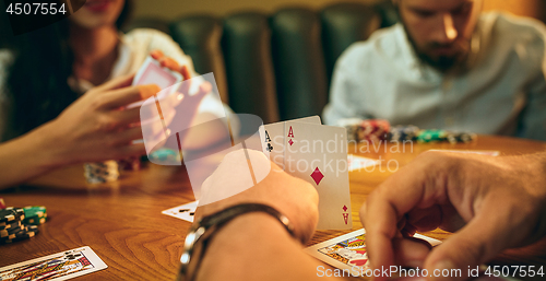 Image of Side view photo of friends sitting at wooden table. Friends having fun while playing board game.